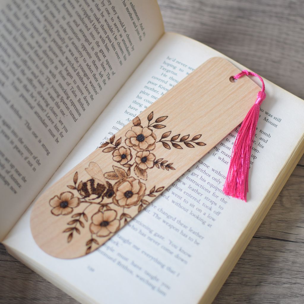 wooden bookmark with a bright pink tassel laid on a open book.