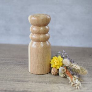 a tall Oak wood turned twig vase next to a posy o dried wild flowers