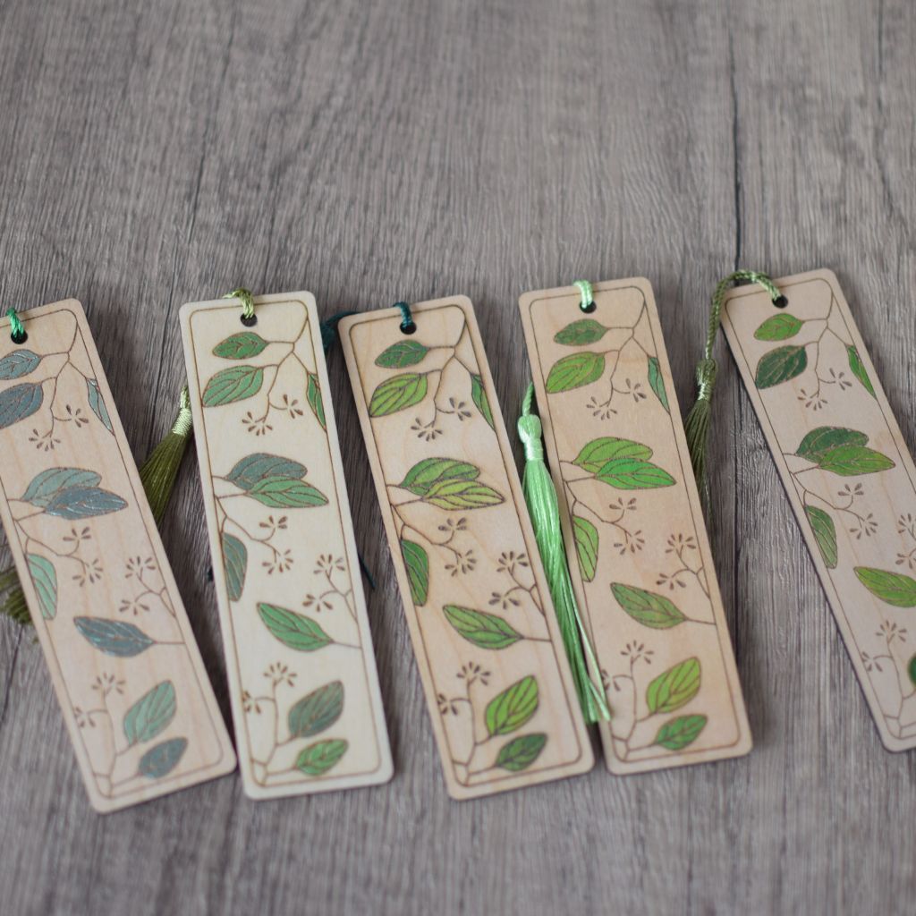 photo showing a group of 5 laser engraved and hand painted book marks with a leaves pattern all painted in shades of green including some metallic shades
