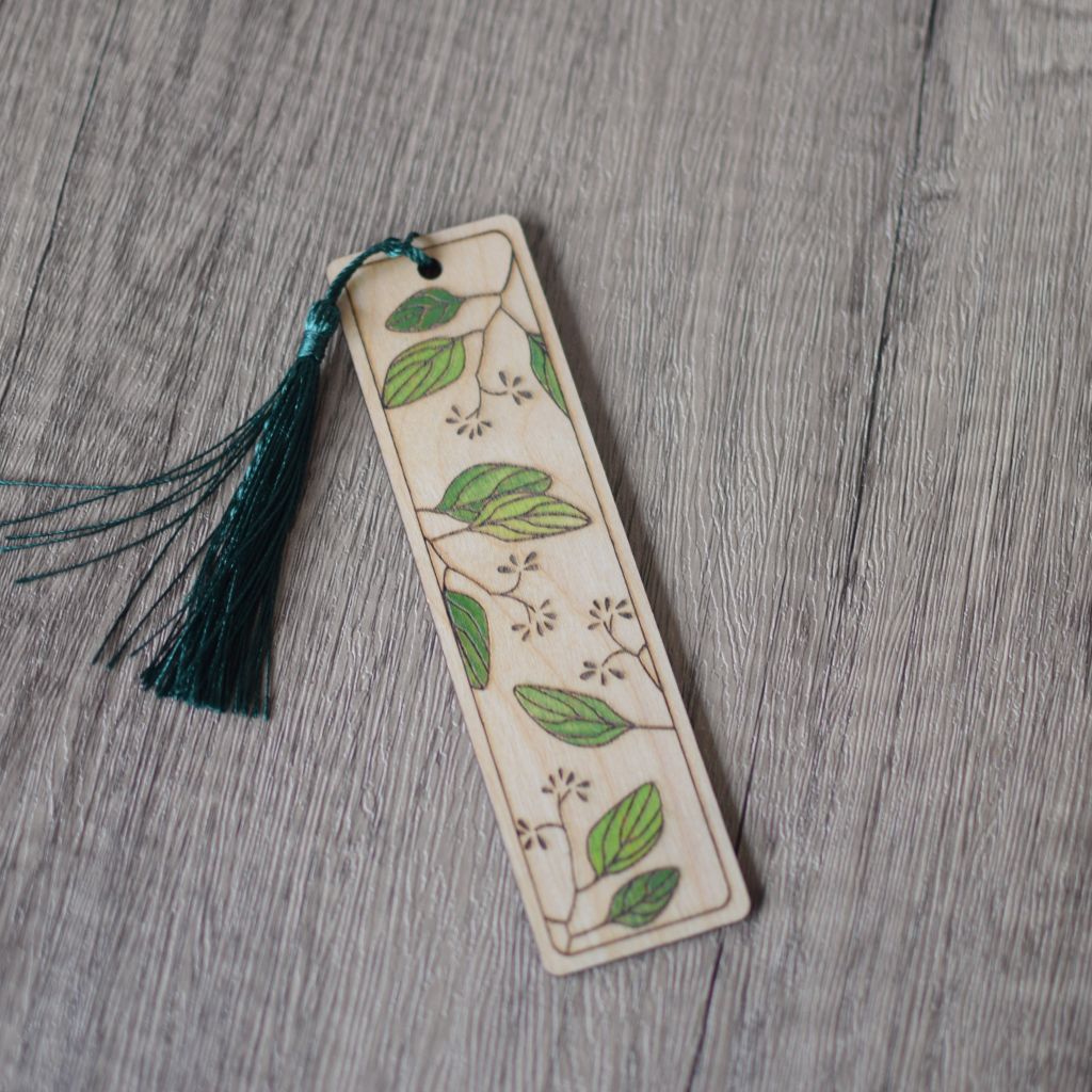 a single laser engraved bookmark with leaves design. The leaves are hand painted in shades of green and there is a dark green silky tassel