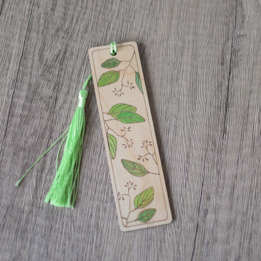 a single laser engraved bookmark with leaves design. The leaves are hand painted in shades of green with a light green silky tassel