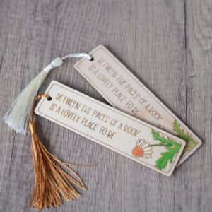 a photo showing two laser engraved bookmarks with cream and bronze coloured tassels with a hand painted daisy design