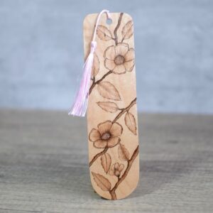 Photo showing an upright wooden bookmark with a pale pink silky tassel. The bookmark features a hand burnt design of blossoms on a branch. The design covers the bookmark.