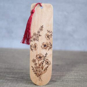Photo showing an upright wooden bookmark with a deep red silky tassel. The bookmark features a posy of wild flowers and blossoms design. The design covers the bookmark