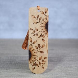 Photo showing a wooden pyrography bookmark and bronze silky tassel. Design is two half sunflowers with leaves