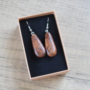 a pair of wooden earrings made form hard wood burl on surgical stainless steel. The earrings are shaped into a long raindrop style.