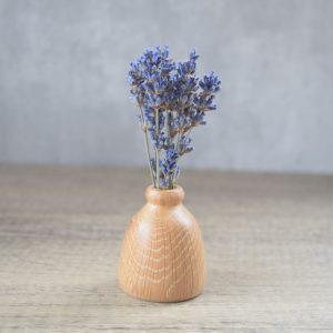A small oak wood turned twig vase with dried lavender sprigs