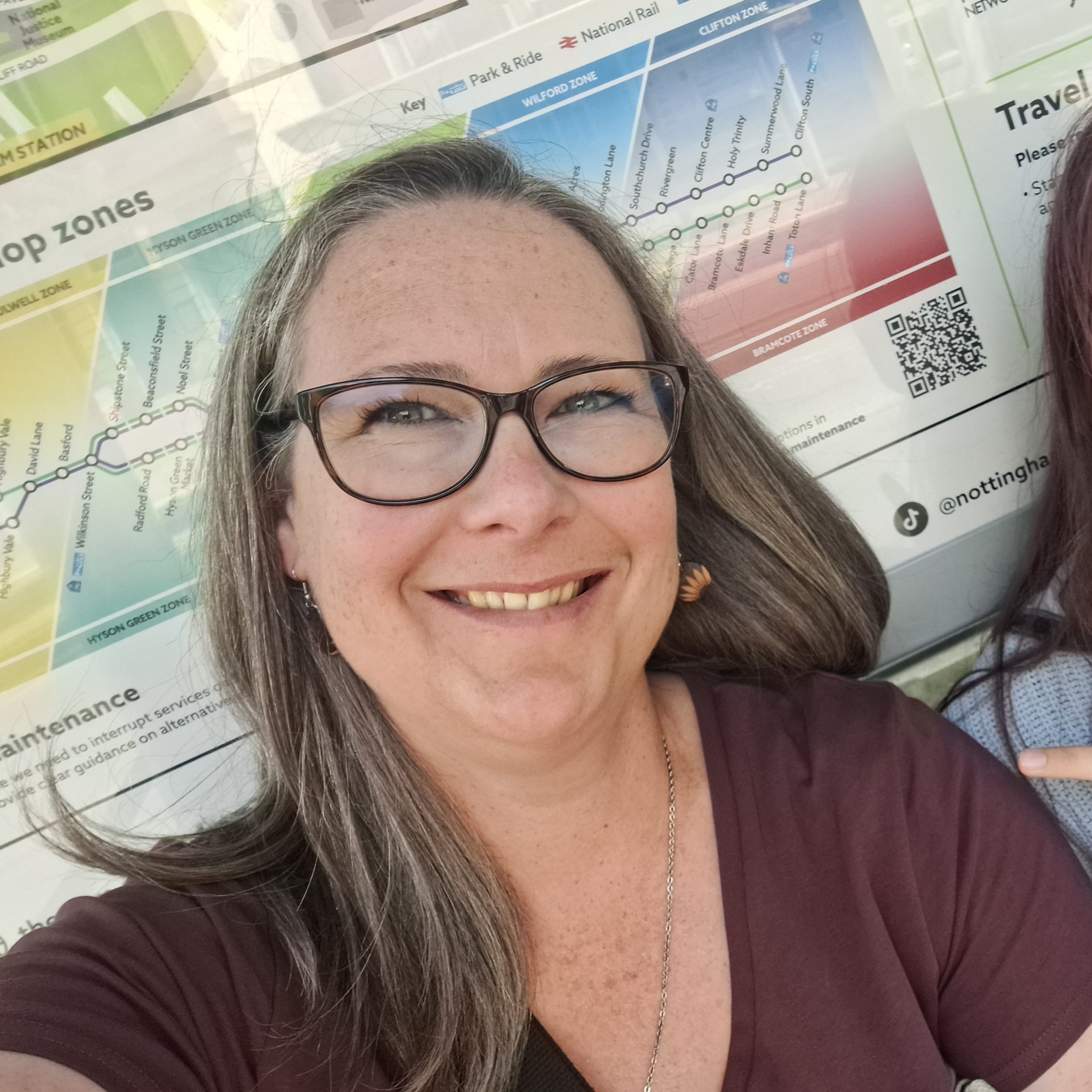 A selfie.  Carrie the CG of CG Wood Crafts.  Photo shows a lady wearing glasses, brown (with quite a bit of grey!) shoulder length hair, smiling. 